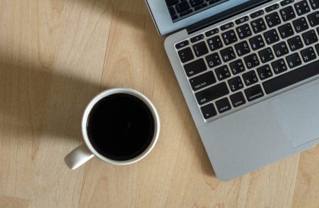 Top view of Laptop, notepad and coffee cup on office wooden background,flat lay