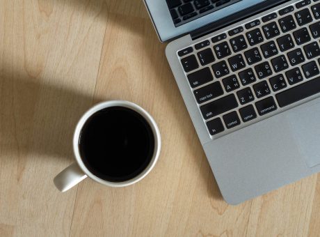 Top view of Laptop, notepad and coffee cup on office wooden background,flat lay